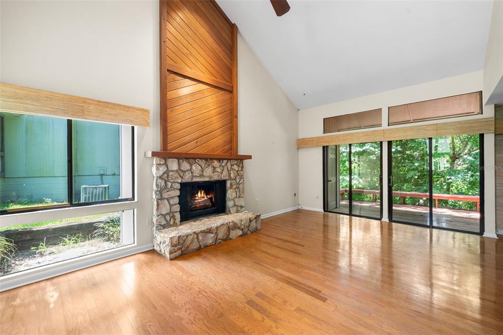A living room features hardwood floors, a stone fireplace, and sliding glass doors to a deck — 1653 NW 19TH CIRCLE, GAINESVILLE, FL