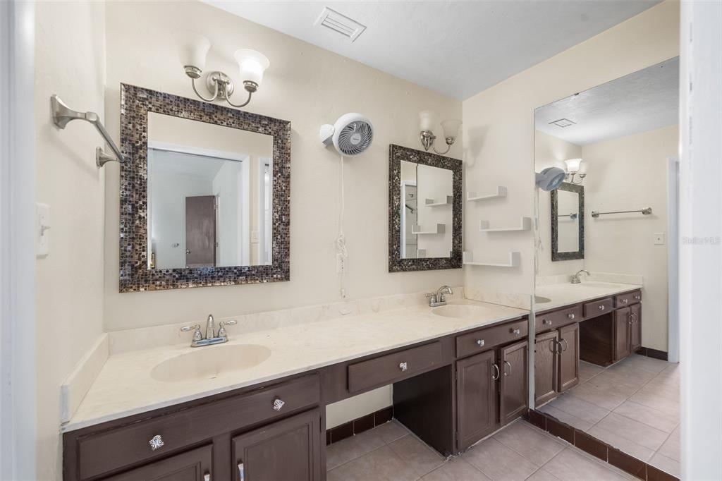 A bathroom features a long vanity with two sinks, dark cabinets, and two framed mirrors — 1653 NW 19TH CIRCLE, GAINESVILLE, FL