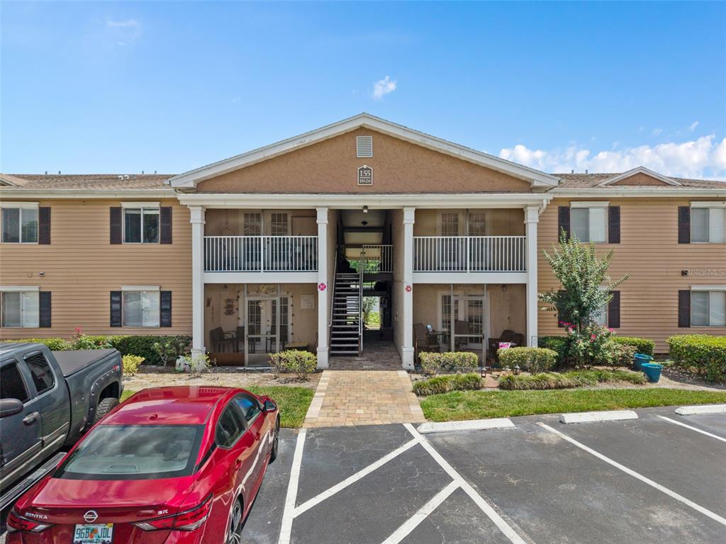 A two-story apartment building with a central staircase and parking lot in the foreground — 155 N PEARL LAKE CAUSEWAY UNIT 208, ALTAMONTE SPRINGS, FL