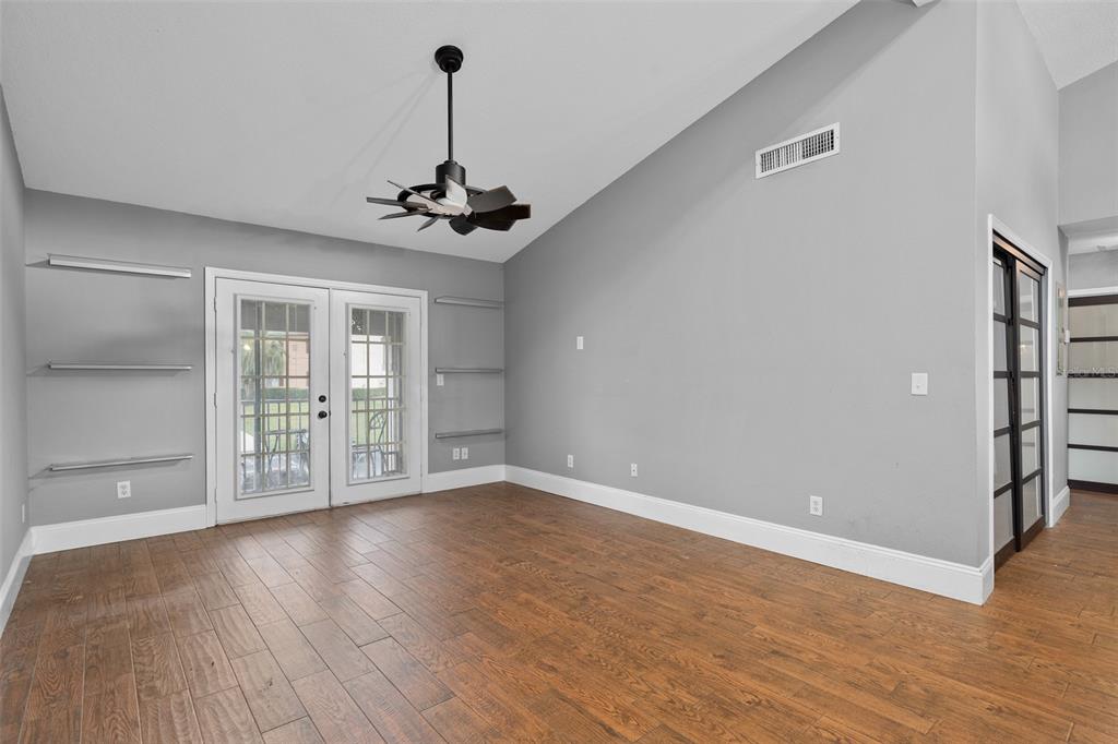 A room with wood-look tile flooring, gray walls, floating shelves, and French doors — 155 N PEARL LAKE CAUSEWAY UNIT 208, ALTAMONTE SPRINGS, FL