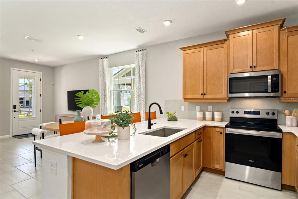 A kitchen features light wood cabinets, white countertops, stainless steel appliances, and an island — 221 SPINDLE PALM COVE, WINTER SPRINGS, FL
