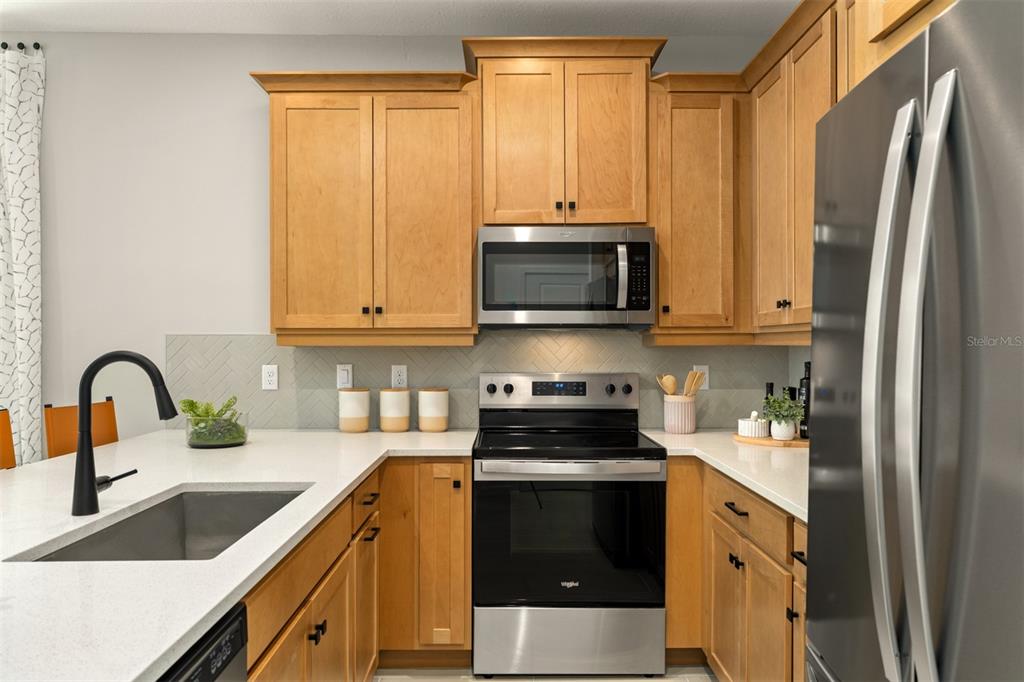 A kitchen features light wood cabinets, stainless steel appliances, and a white countertop — 221 SPINDLE PALM COVE, WINTER SPRINGS, FL