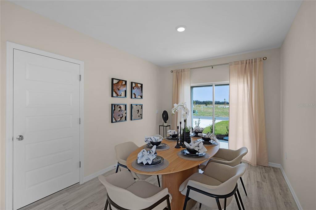 A dining room features an oval wooden table, four chairs, and a sliding glass door — 1738 HUMMINGBIRD ROAD, WINTER HAVEN, FL
