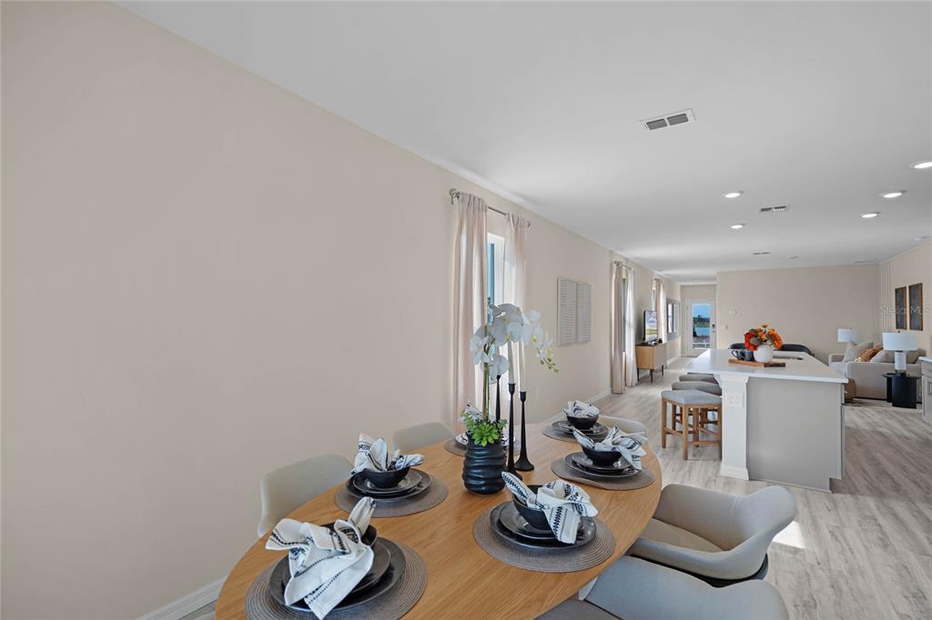 A dining area with a wooden table leads into an open-concept kitchen and living space — 1738 HUMMINGBIRD ROAD, WINTER HAVEN, FL