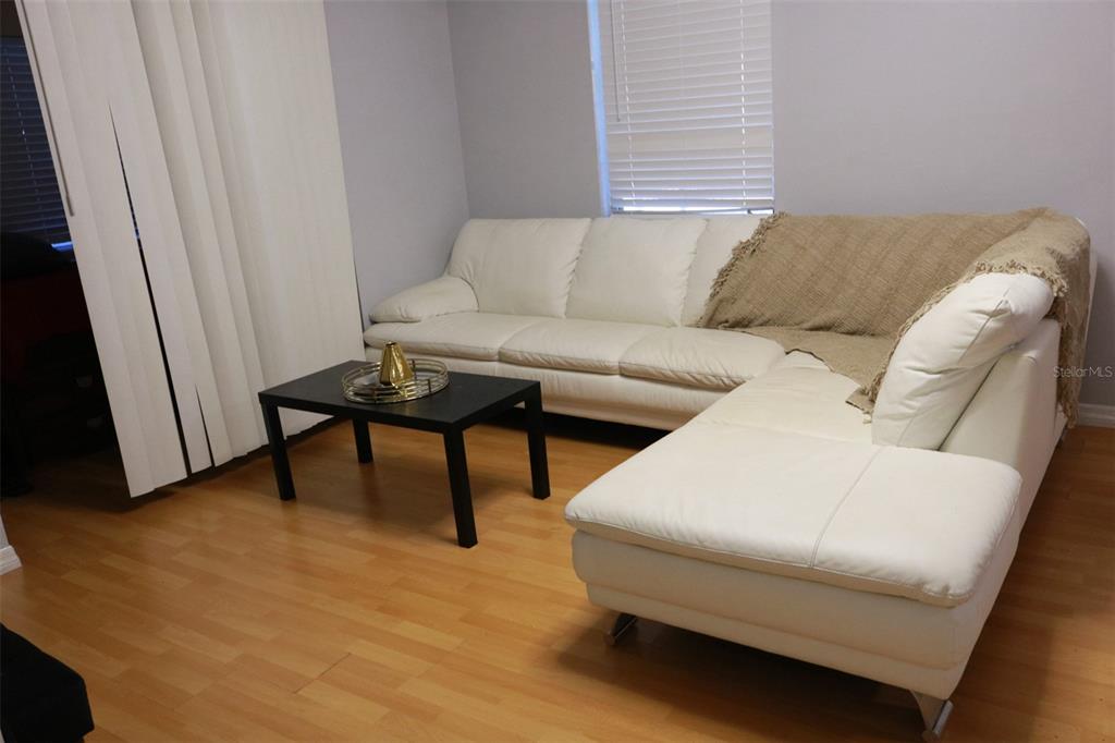 A living room features a white sectional sofa, a black coffee table, and wood flooring — 3125 36TH STREET N UNIT 103, ST PETERSBURG, FL