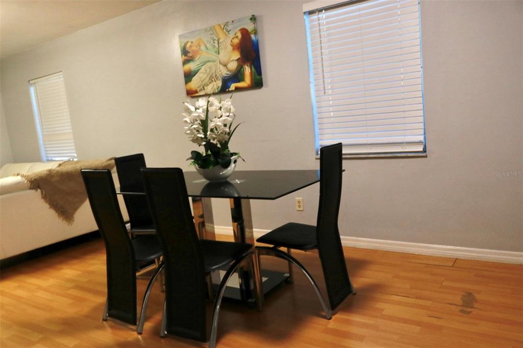A dining area features a glass table, four black chairs, and wall art — 3125 36TH STREET N UNIT 103, ST PETERSBURG, FL