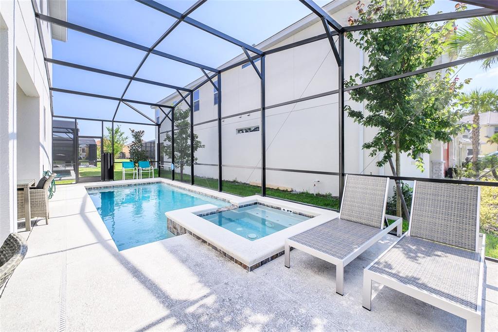 A screened-in patio features a swimming pool, a spa, and two lounge chairs — 2567 SHANTI DRIVE, KISSIMMEE, FL