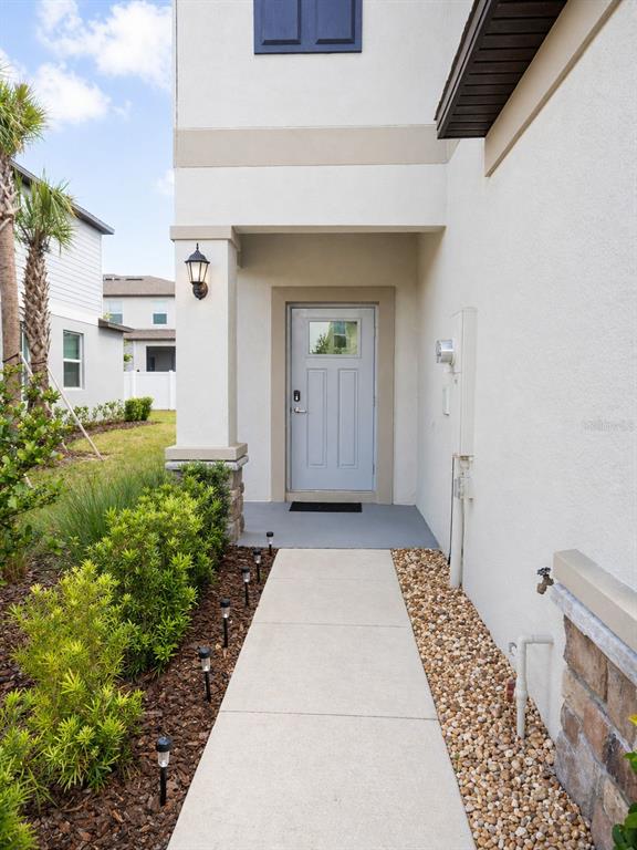 A concrete walkway leads to the front door of a house with a stucco exterior — 36384 WELL HILL WAY, ZEPHYRHILLS, FL