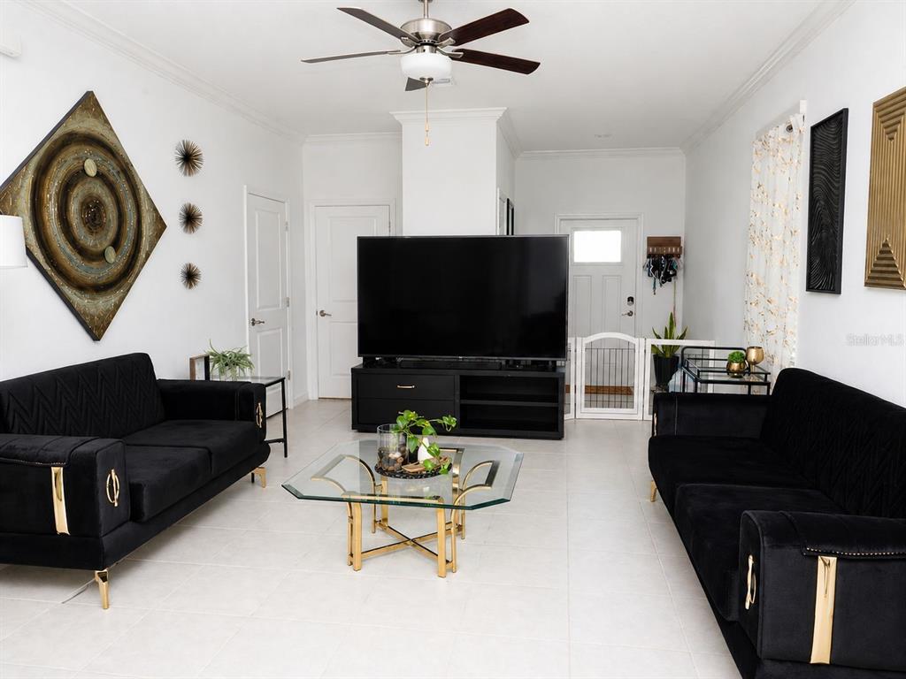 A living room features two black velvet sofas, a glass coffee table, and a large television — 36384 WELL HILL WAY, ZEPHYRHILLS, FL