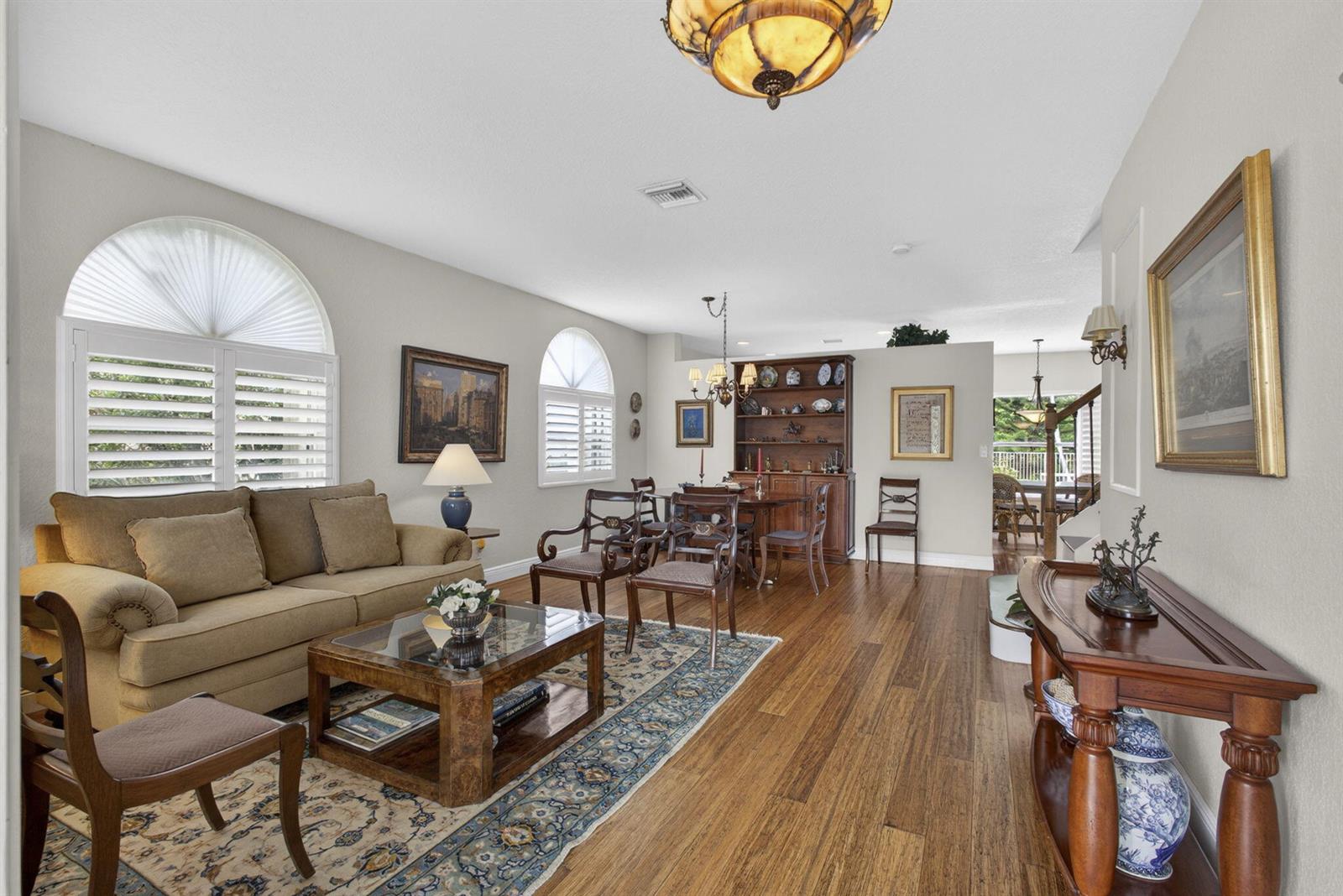A living and dining area with hardwood floors, arched windows, and traditional wooden furniture — 4017 Bluff Harbor Way, Wellington FL 33449, WELLINGTON, FL
