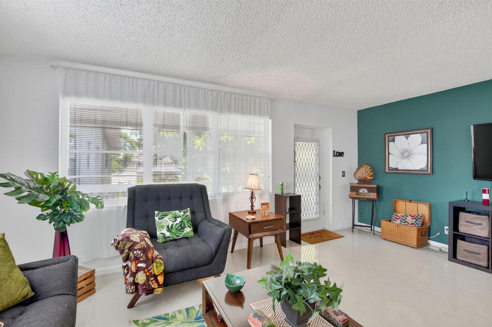 A living room features a teal accent wall, gray armchairs, and a large window — 425 Durham N, Deerfield Beach FL 33442, DEERFIELD BEACH, FL
