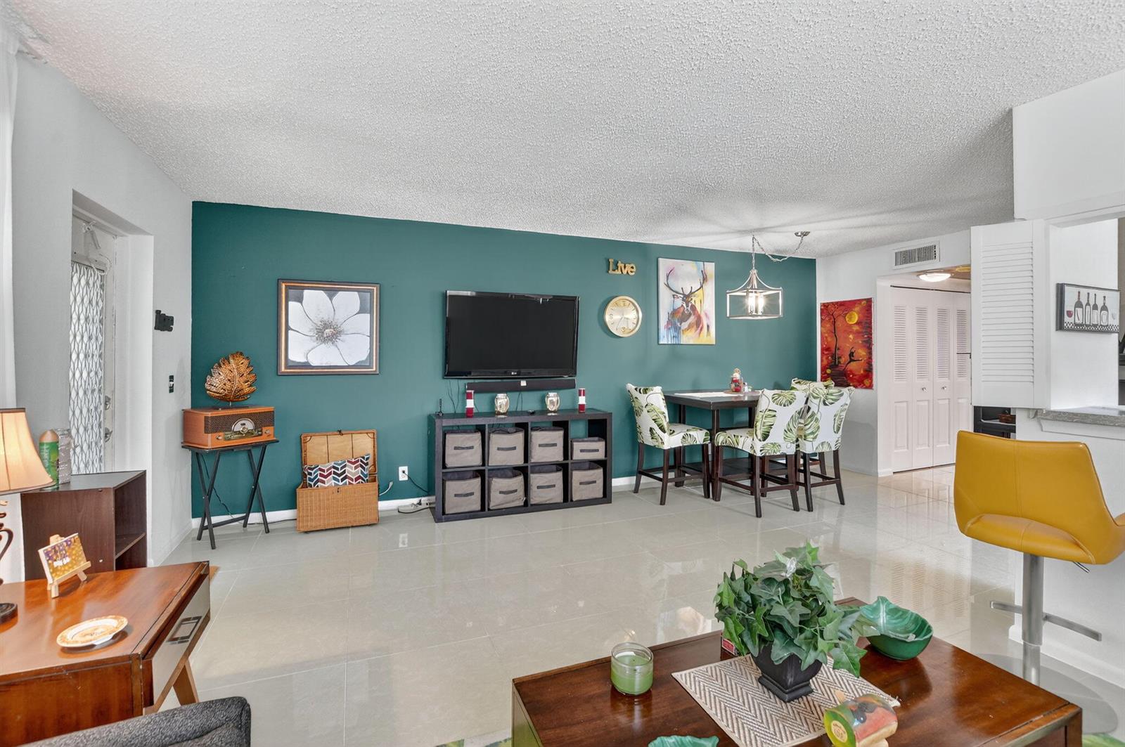 A living and dining area features a teal accent wall, tile flooring, and modern furniture — 425 Durham N, Deerfield Beach FL 33442, DEERFIELD BEACH, FL