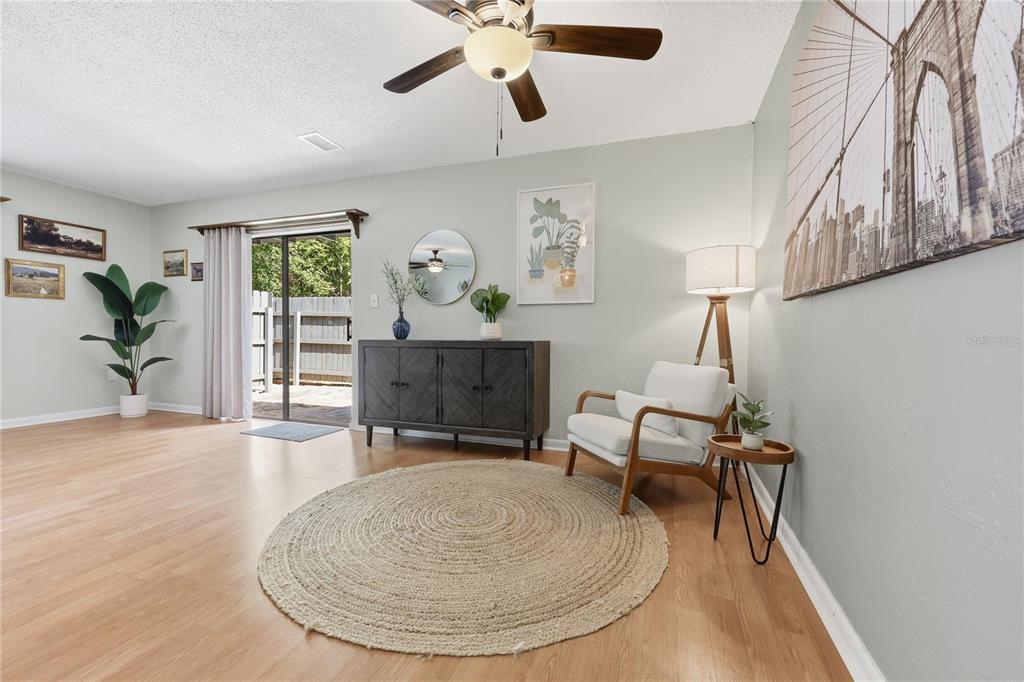 A living room features light wood flooring, a circular rug, a sideboard, and an armchair — 4109 NW 43RD TERRACE UNIT 69, GAINESVILLE, FL