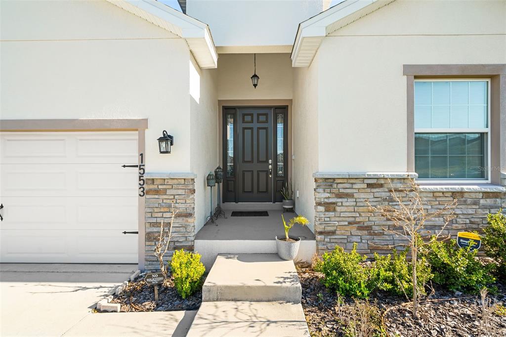 A kitchen features white cabinets, a marble-topped island with bar stools, and stainless steel appliances — 1553 FLEUR DRIVE, DAVENPORT, FL