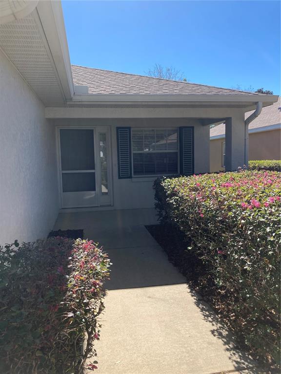 A concrete walkway leads to the front entrance of a house with a covered porch — 9505 SW 93 LOOP, OCALA, FL