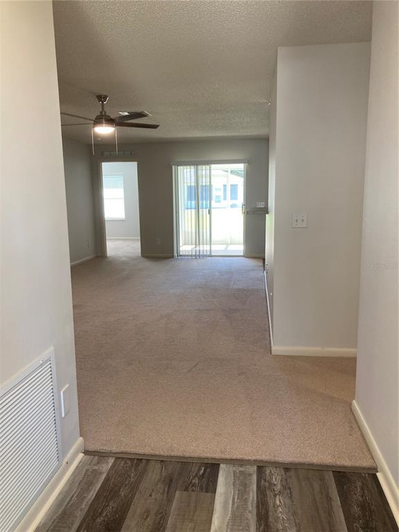 A view from a hallway looking into a carpeted living area with a ceiling fan — 9505 SW 93 LOOP, OCALA, FL