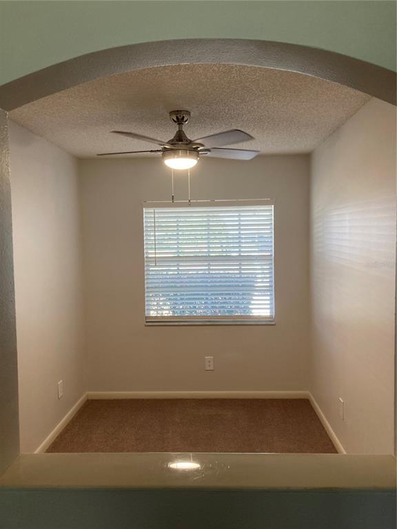 A small, carpeted room features an arched entryway, a ceiling fan, and a single window — 9505 SW 93 LOOP, OCALA, FL