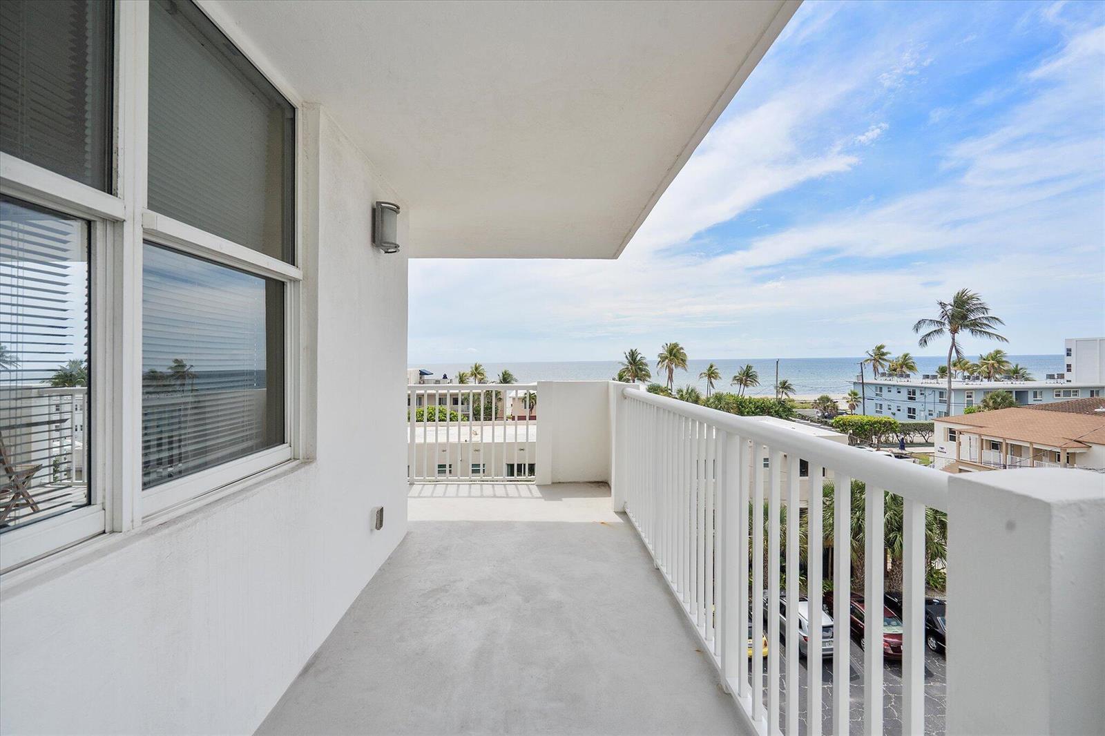 A white balcony overlooks a coastal view with palm trees, buildings, and the ocean — 1601 S Ocean Drive # 506, Hollywood FL 33019, HOLLYWOOD, FL