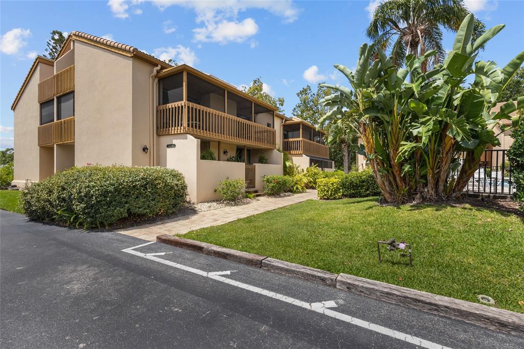 A multi-story tan apartment building features screened balconies and a landscaped lawn with palm trees — 3037 WILLOW GREEN DRIVE UNIT 12, SARASOTA, FL