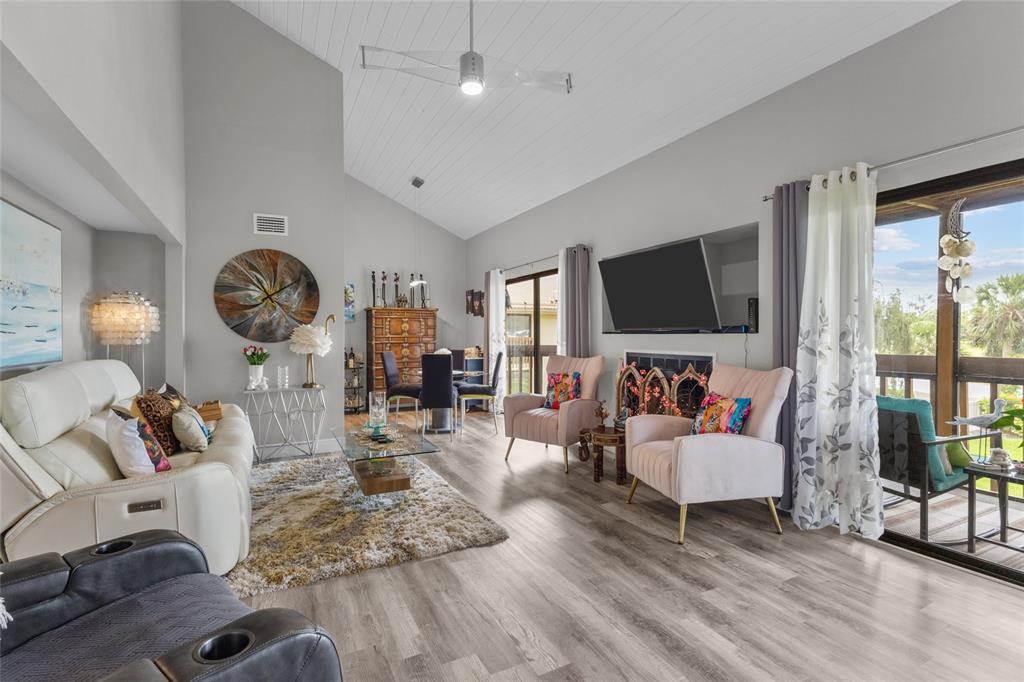 A living room features vaulted ceilings, light wood flooring, a fireplace, and a sliding door — 3037 WILLOW GREEN DRIVE UNIT 12, SARASOTA, FL