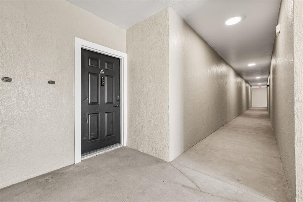 A black apartment door with the number 304 is located in a long, beige hallway — 3315 PARKCHESTER SQUARE BOULEVARD UNIT 304, ORLANDO, FL