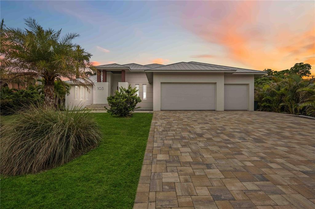 A modern single-story house with a paver driveway, three-car garage, and a palm tree — 103 GRAHAM STREET SE, PORT CHARLOTTE, FL