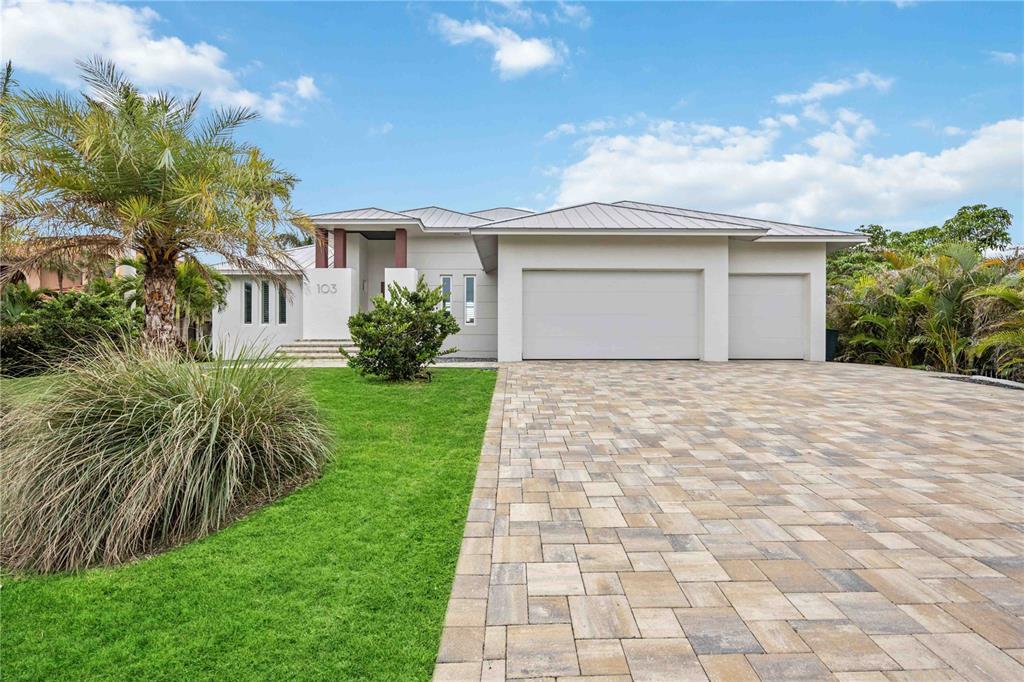 A modern single-story house features a paved driveway, a three-car garage, and a palm tree — 103 GRAHAM STREET SE, PORT CHARLOTTE, FL