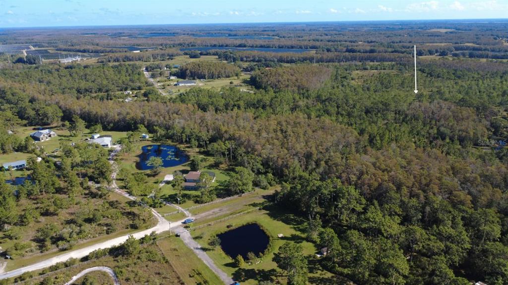 An aerial view shows a rural property with wooded areas, two ponds, and nearby houses — 0 CYPRESS CREEK RANCH ROAD, ST CLOUD, FL