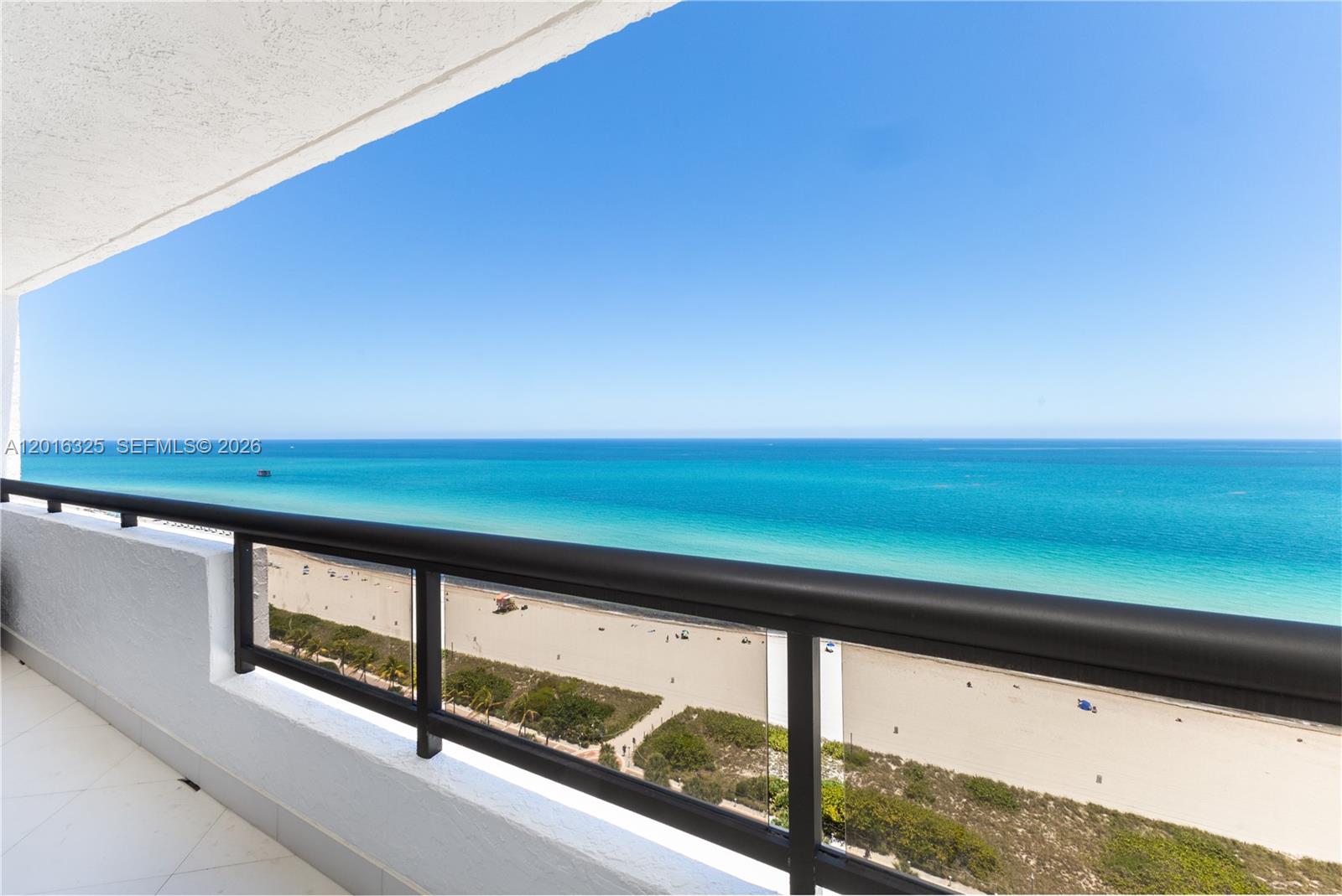 A balcony with a black metal railing overlooks a sandy beach and the ocean — 2555 Collins Ave # 2205, Miami Beach FL 33140, MIAMI BEACH, FL