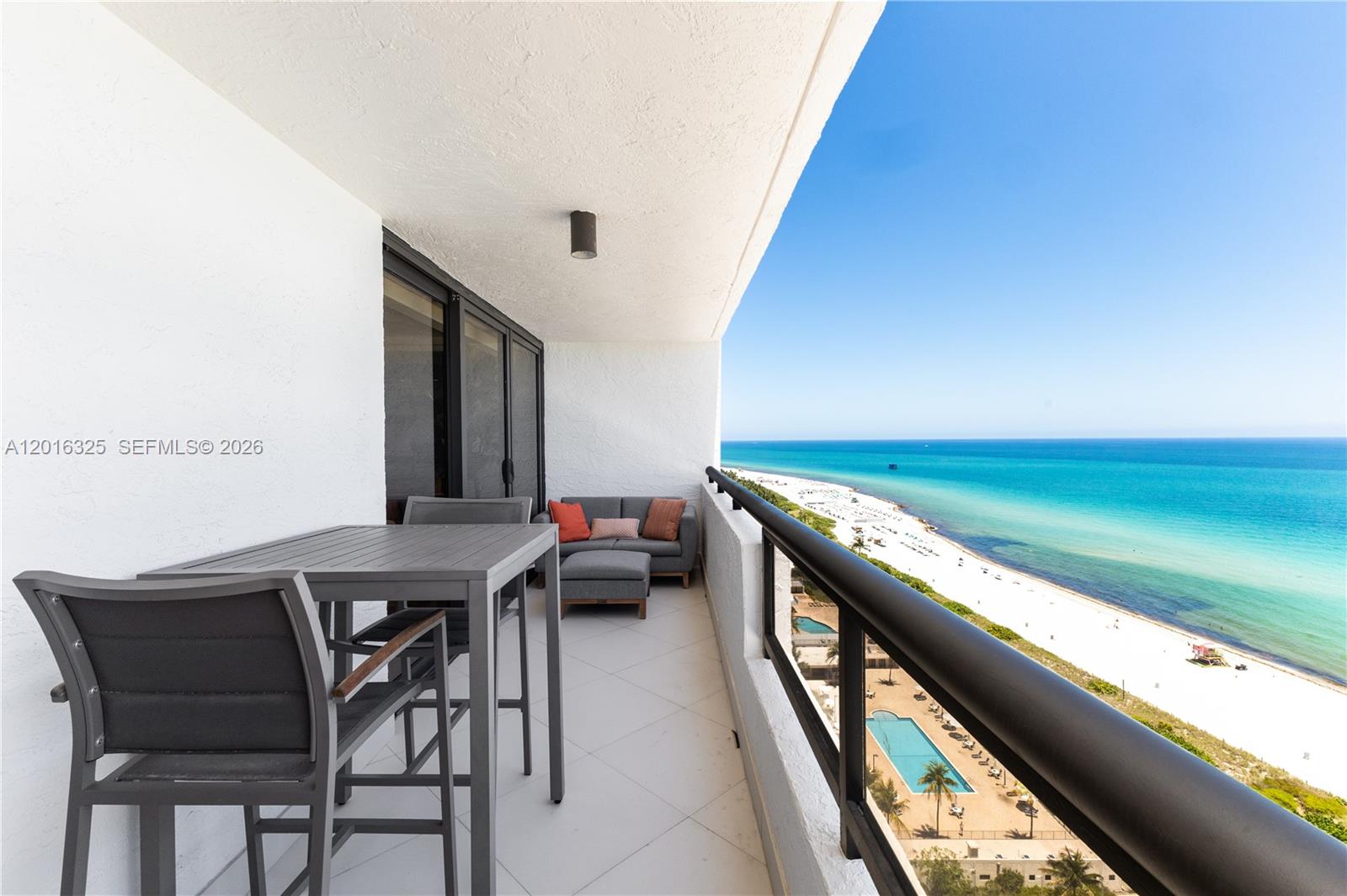 A balcony with outdoor furniture overlooks a sandy beach and the ocean — 2555 Collins Ave # 2205, Miami Beach FL 33140, MIAMI BEACH, FL