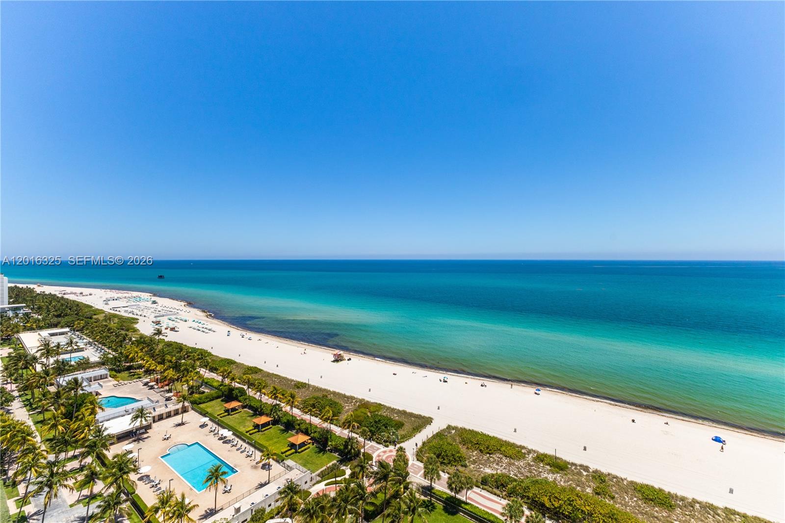 An aerial view shows a sandy beach, turquoise ocean, and a swimming pool area — 2555 Collins Ave # 2205, Miami Beach FL 33140, MIAMI BEACH, FL