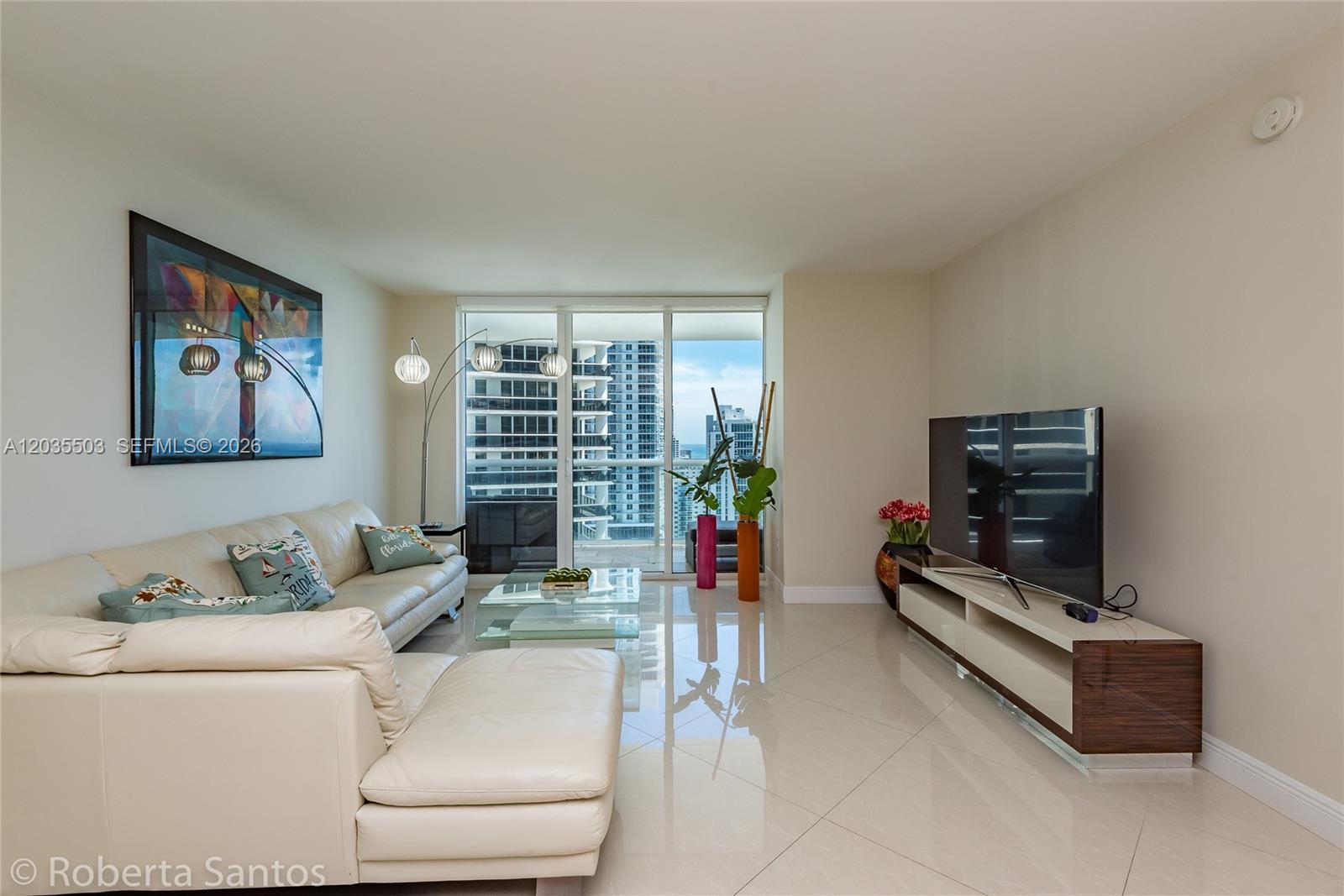 A modern living room features a white sectional sofa, glass coffee table, and city views — 1830 S Ocean Dr # 2410, Hallandale Beach FL 33009, HALLANDALE BEACH, FL
