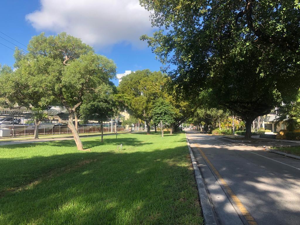 A paved road runs alongside a grassy park area with mature trees and a boat yard — 1975 NE 135th St # 2D, North Miami FL 33181, NORTH MIAMI, FL
