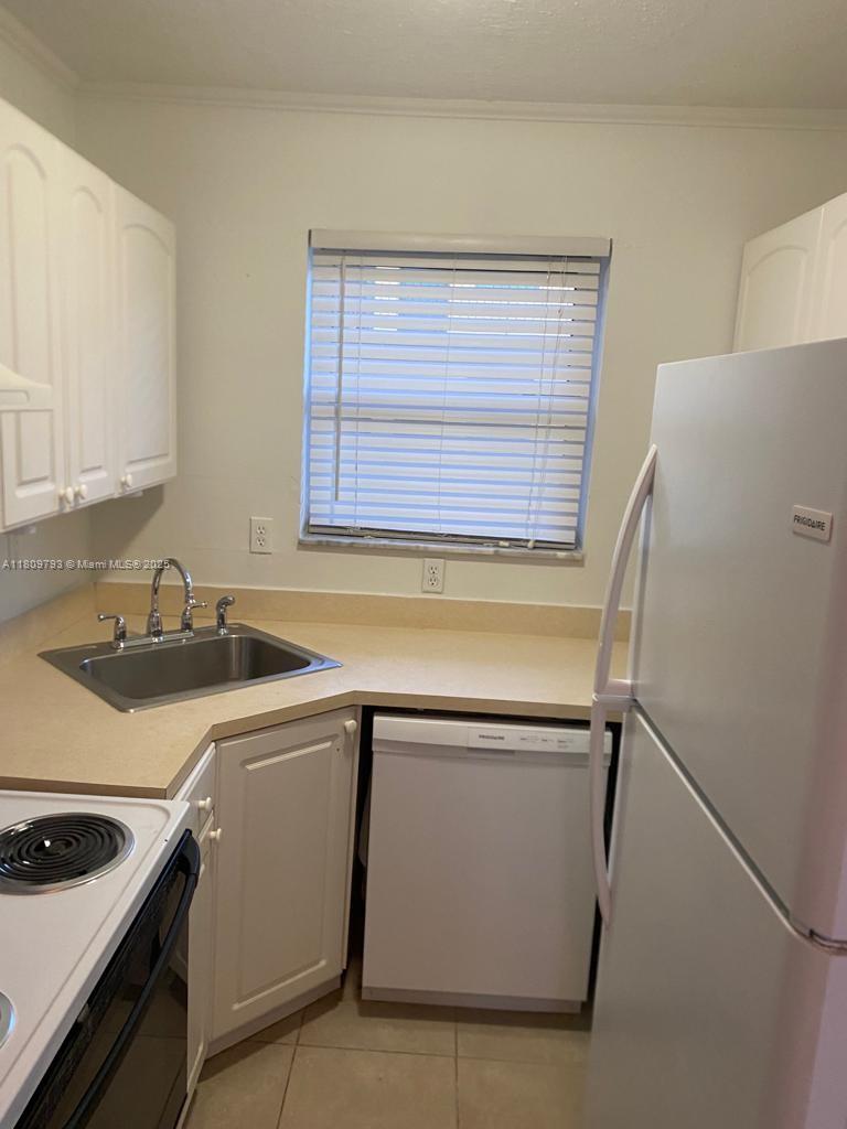 A kitchen features white cabinets, a stainless steel sink, a dishwasher, and a white refrigerator — 1975 NE 135th St # 2D, North Miami FL 33181, NORTH MIAMI, FL