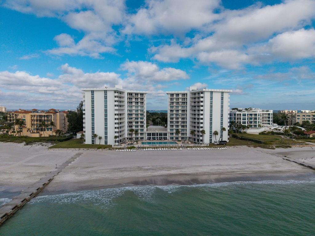 An aerial view of a tall beachfront condominium building with a pool and sandy beach — 2295 GULF OF MEXICO DRIVE UNIT 54S, LONGBOAT KEY, FL