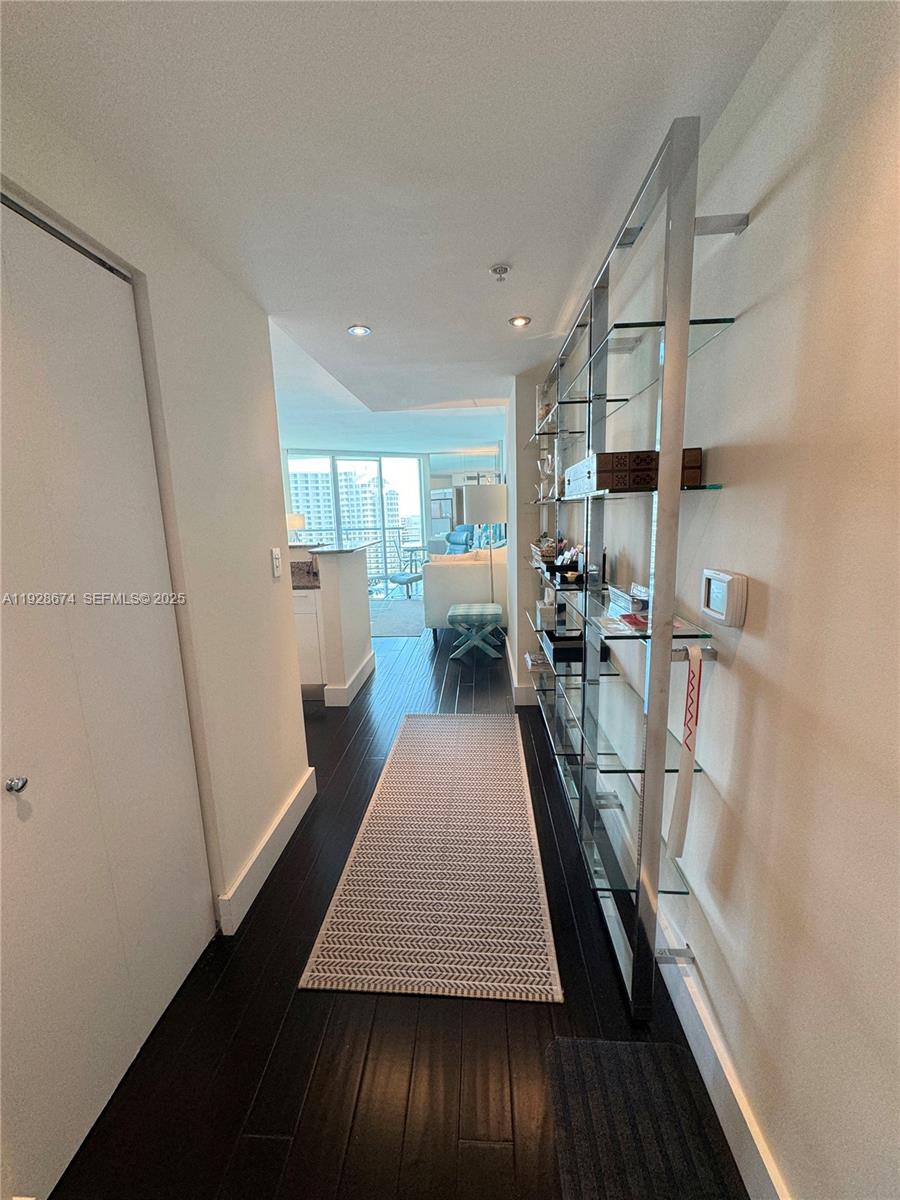 A hallway with dark wood floors leads to a living area with floor-to-ceiling windows — 335 S Biscayne Blvd # 2403, Miami FL 33131, MIAMI, FL