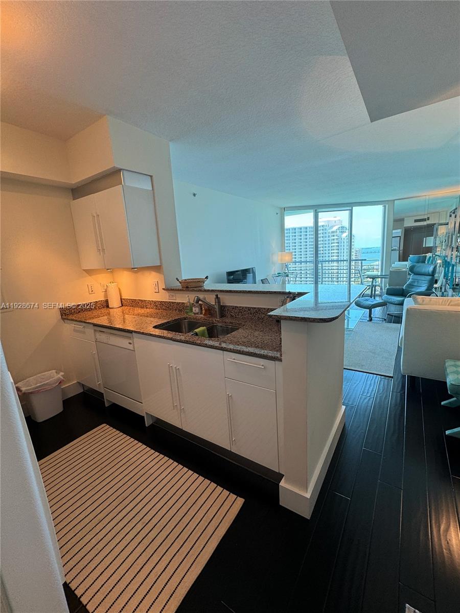 A kitchen with white cabinets, granite countertops, and a view of high-rise buildings outside — 335 S Biscayne Blvd # 2403, Miami FL 33131, MIAMI, FL