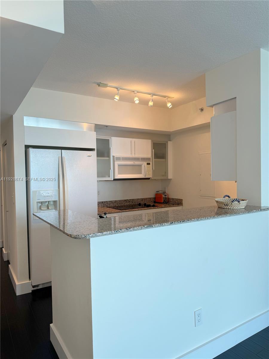 A kitchen features white cabinetry, granite countertops, a breakfast bar, and stainless steel appliances — 335 S Biscayne Blvd # 2403, Miami FL 33131, MIAMI, FL