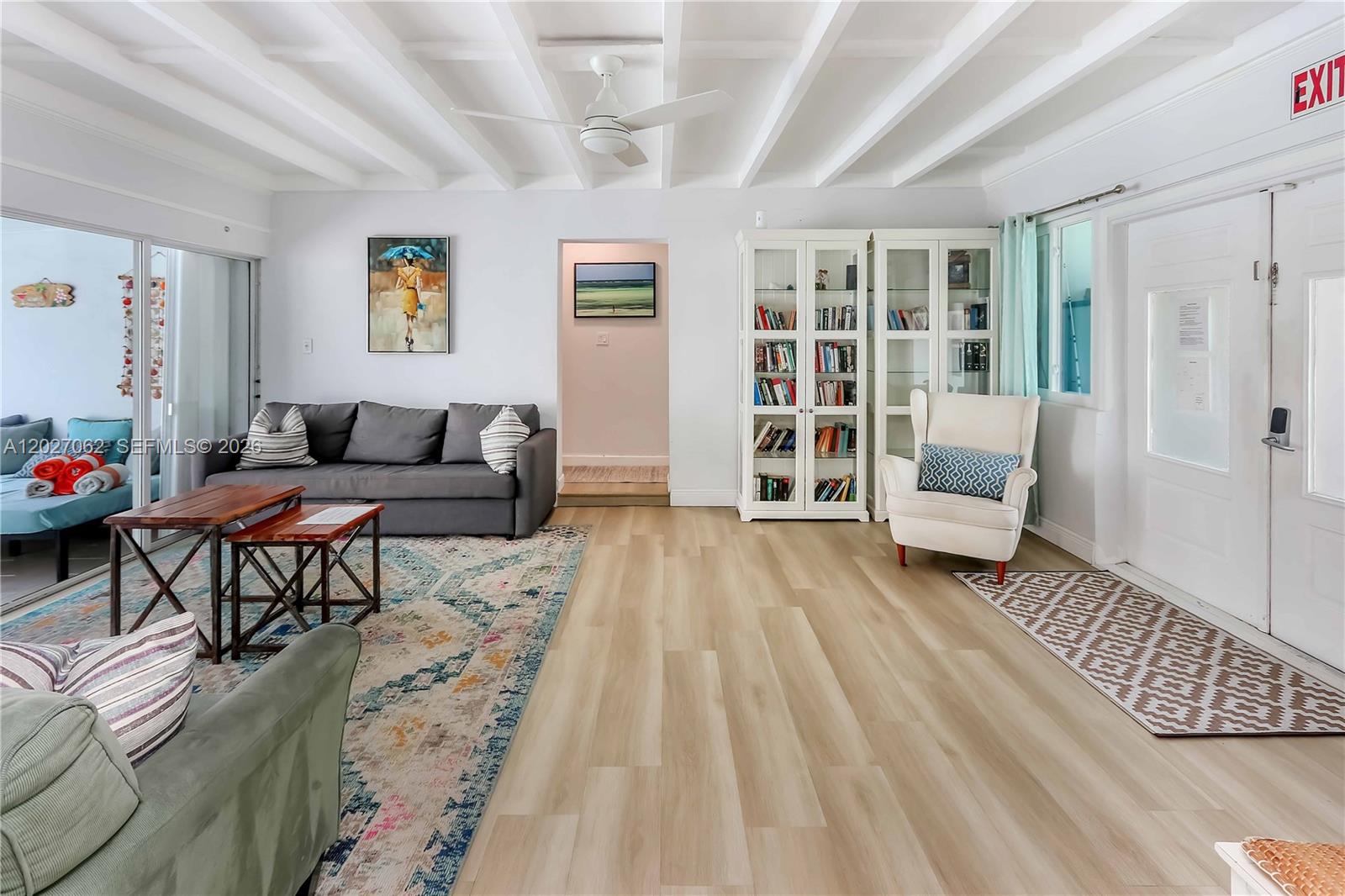A living room features a gray sofa, white bookshelves, a ceiling fan, and light wood flooring — 955 Van Buren St, Hollywood FL 33019, HOLLYWOOD, FL
