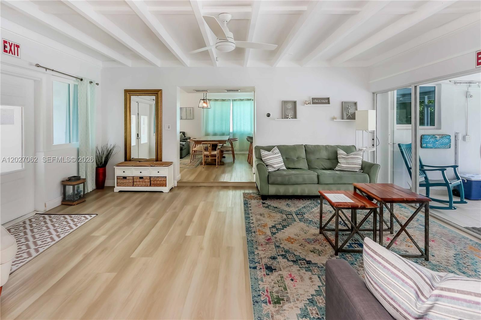 A living room with light wood floors, a green sofa, and a white beamed ceiling — 955 Van Buren St, Hollywood FL 33019, HOLLYWOOD, FL