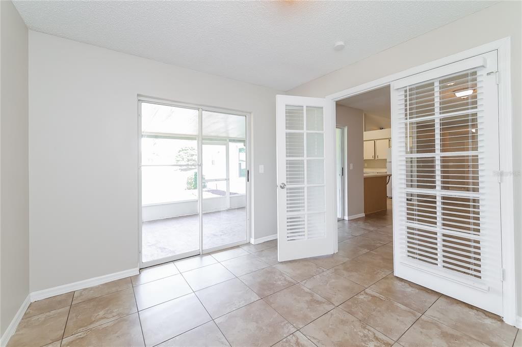 A room with tiled flooring, a sliding glass door, and French doors leading to a kitchen — 177 TORTUGA COURT, DAVENPORT, FL