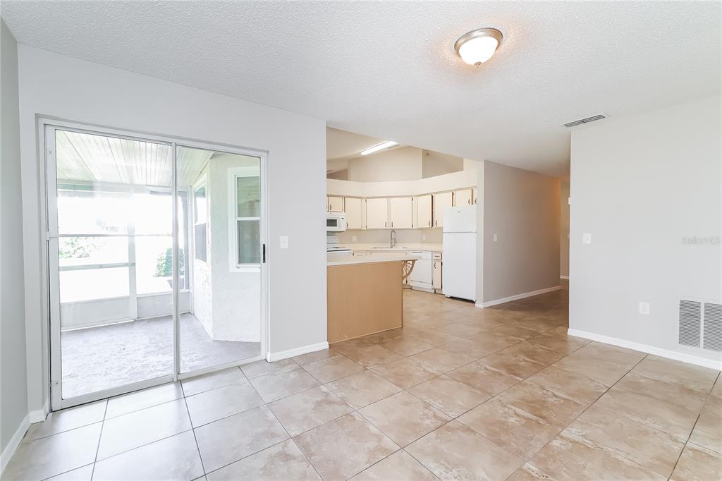 A tiled dining area leads to a kitchen with white cabinets and a sliding glass door — 177 TORTUGA COURT, DAVENPORT, FL