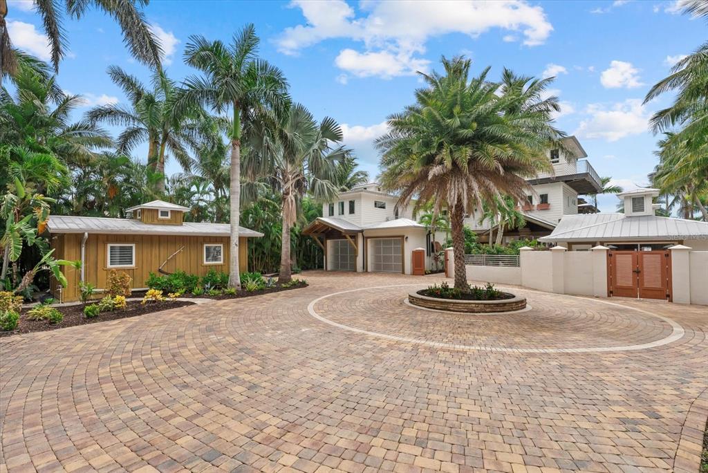 A circular paver driveway leads to a multi-story house with a detached wooden shed — 10216 46TH AVENUE W, BRADENTON, FL