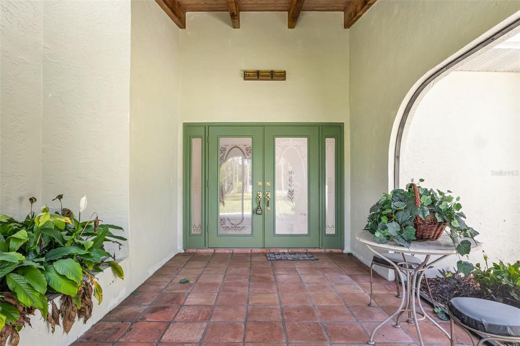 A covered entryway features a tiled floor, green double doors, and a small bistro table — 6068 TIDWELL STREET, NORTH PORT, FL