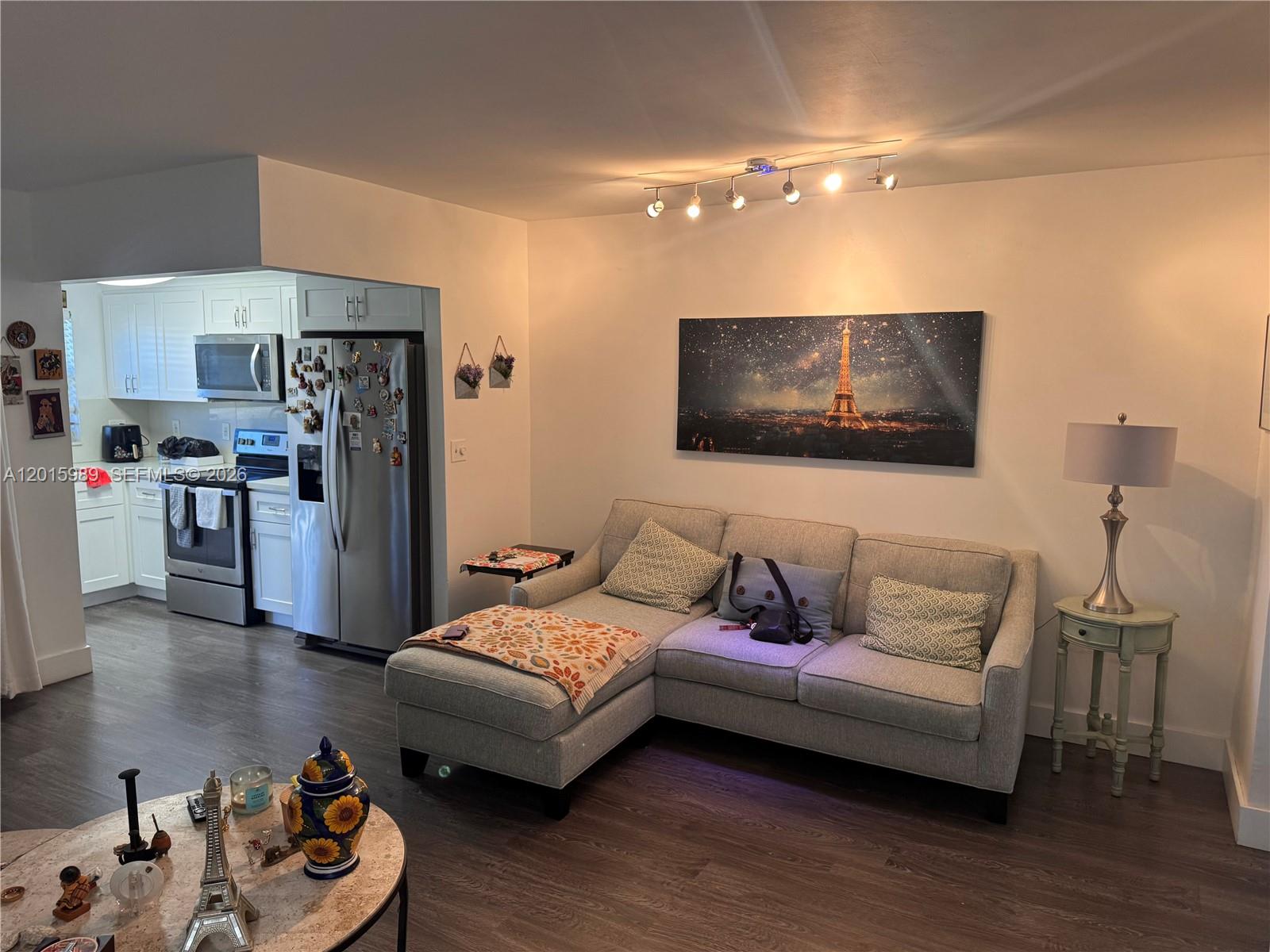 A living room with a gray sectional sofa, Eiffel Tower wall art, and an adjacent kitchen — 5300 Washington St # J214, Hollywood FL 33021, HOLLYWOOD, FL