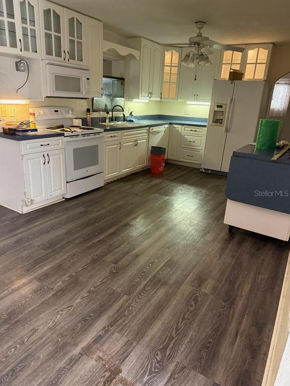 A kitchen features white cabinets, dark countertops, wood-look flooring, and a white refrigerator — 3224 NW 30TH PLACE, GAINESVILLE, FL