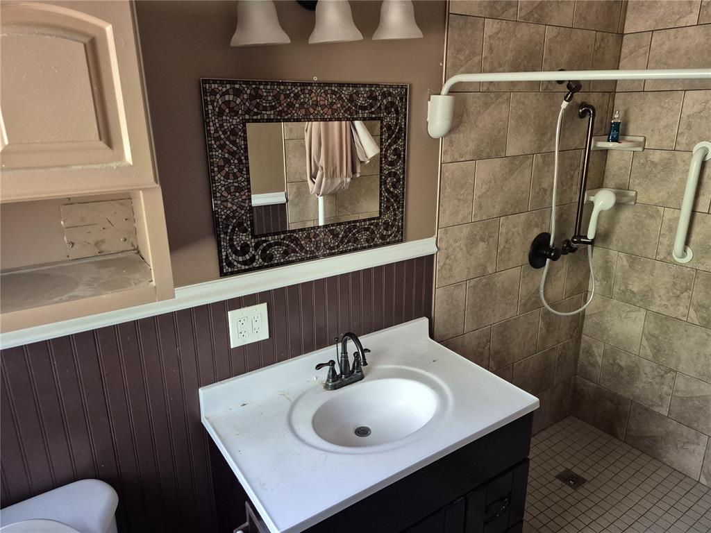 A bathroom features a dark vanity, a mosaic-framed mirror, and a tiled walk-in shower — 3224 NW 30TH PLACE, GAINESVILLE, FL