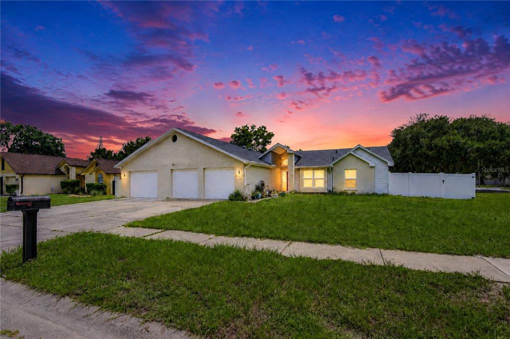 A single-story house with a three-car garage and a lawn at sunset — 1108 DOCKSIDE DRIVE, LUTZ, FL