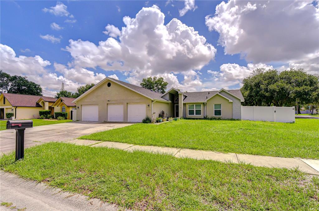 A single-story house with a three-car garage and a large front lawn under a cloudy sky — 1108 DOCKSIDE DRIVE, LUTZ, FL