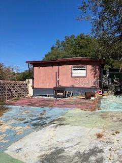 The exterior of a weathered mobile home features a faded red facade and concrete patio — 126 YEATTS AVENUE, INTERLACHEN, FL